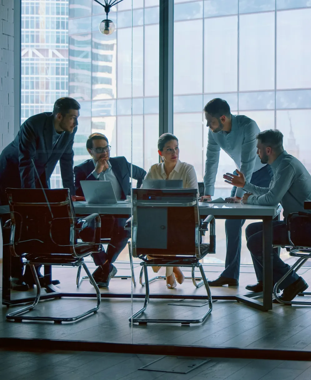 会議室でノートPCを囲みながら打ち合わせを行うビジネスチーム